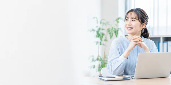 笑顔でデスクに座る若い女性